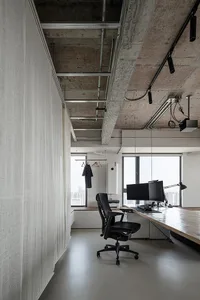 A modern industrial-style workstation with a concrete desk, black office chair, and minimalistic design elements.