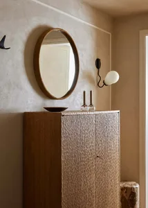 Mid-century modern cabinet with a circular mirror and a sconce lamp on the wall