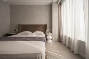 Modern minimalist bedroom featuring a sleek white bed with a glass and metal headboard, clean lines, and a cozy atmosphere cr