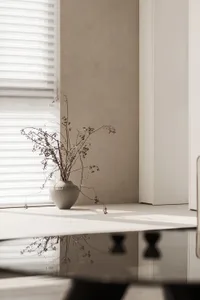 A minimalist interior space with concrete elements and a vase of dried flowers.