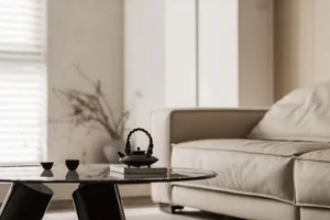 Minimalist living room featuring a glass coffee table and a leather sofa.