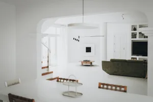 A minimalist living room featuring white tiles, a green sofa, and a modern coffee table with chess pieces.