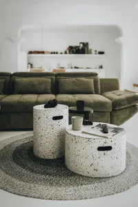 A modern living room with concrete furniture and a green sofa.