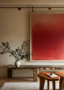 A modern living room featuring concrete and wooden furniture, with a red abstract painting on the wall and a plant in a vase 