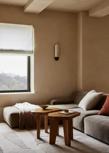 A modern minimalist living room with fabric furniture and wall sconce.