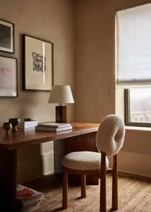 A modern home office setup featuring a wooden desk, chair, and framed artwork.