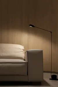 A modern white couch with a floor lamp beside it in a well-lit room.