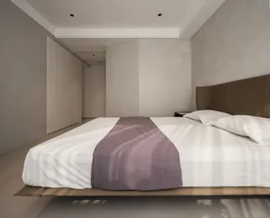 A minimalist bedroom featuring concrete walls, fabric bedding, and wood accents.