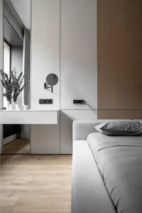 Modern, minimalist bedroom featuring grey furniture and wooden flooring.