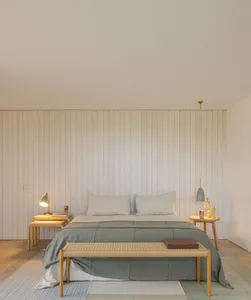 A minimalist bedroom with white walls, light wood furniture, and minimal decorative elements.