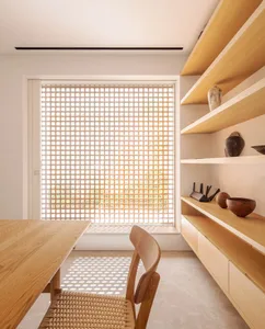 A modern minimalist home office featuring wooden furniture, featuring a table, chairs, and built-in shelves.
