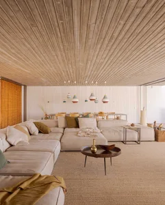 Minimalist living room with concrete walls and ceiling, featuring a large sectional sofa and a coffee table.