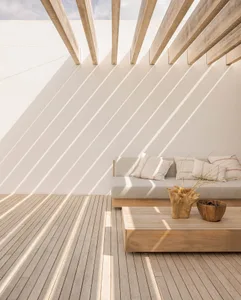 A minimalist patio featuring a wooden table and sofa with light and shadows cast by structural beams.