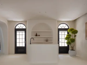 Modern minimalist living room with white walls and floor, featuring a circular structure with a sink and floating shelves.