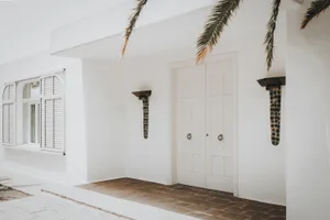 White-walled concrete building with black sconces and tiled floor.