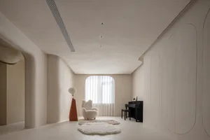 A modern living room with minimalist decor, featuring a white armchair, a black piano, and a unique floor lamp with a red bas