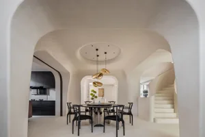 A modern dining room with concrete flooring, a circular table, and black chairs.