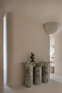 A modern entryway featuring a marble console table with a black abstract sculpture on top.