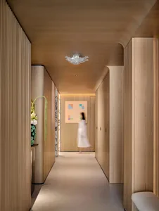A modern interior with wooden paneling, a crystal chandelier, and a blurred figure walking through the hallway.