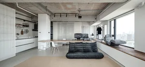 A modern living/office space featuring concrete floors, white walls, and a wooden desk.