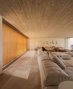 A modern living room with concrete walls, a large sectional sofa, and a patterned rug.