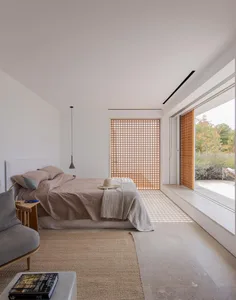 Bedroom with minimalist design, concrete flooring, wooden accents, and fabric bedding.