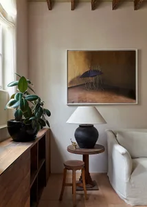 A minimalist interior featuring a white sofa, a black lamp, and a potted plant.
