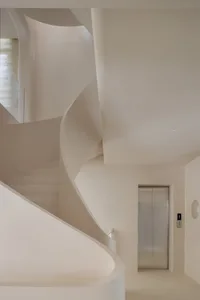 A modern, minimalist spiral staircase made of concrete