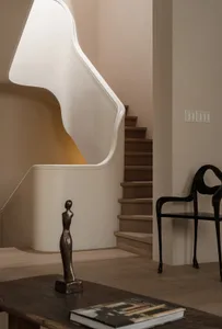 A modern staircase made of wood with a curved white handrail and wooden steps, leading to a second level.