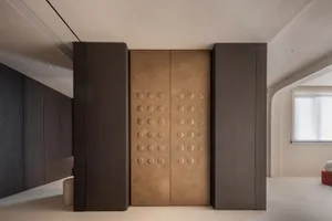 Modern interior featuring a wardrobe with a bronze-colored door and dark timber columns on either side.