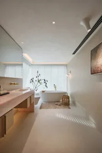 A minimalist bathroom with a concrete floor and walls, featuring a standalone bathtub, a vanity with a pink countertop, and a