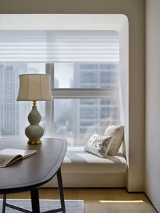 A minimalist home office space with a window seat, an oval table, and a lamp.