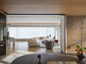 A modern, minimalist living room with wooden furniture and a large window.