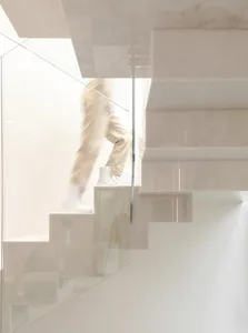 A minimalist staircase with white concrete and glass railings.