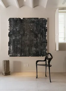A large, black acrylic painting with an expressionistic texture hanging on a wall.