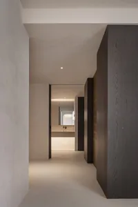 A minimalistic residential bathroom with dark wood accents and beige tiled flooring and walls