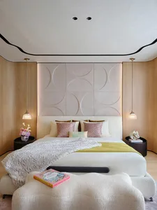 Modern bedroom with a bed adorned with pillows and blankets, featuring a wooden headboard and fabric textures.