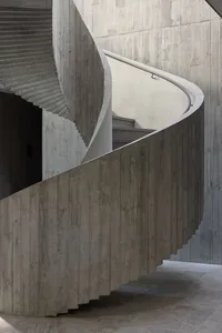 A modern concrete staircase with smooth, curved steps and a handrail.