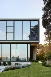 Modern house exterior featuring large glass windows and landscaped garden.