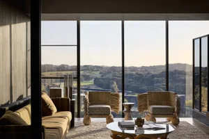 Modern living room with large glass windows overlooking scenic landscape.