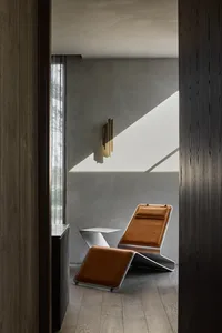 A modern interior design featuring a metallic chair with brown leather upholstery and a small white table.