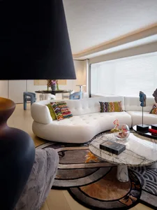 Modern living room featuring a white leather couch, colorful throw pillows, and a round coffee table.
