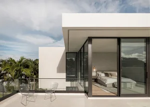 A modern, minimalist bedroom featuring glass walls, a wooden floor, and concrete accents.