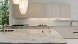 Modern, minimalist kitchen featuring stone countertops and sleek, light-colored cabinets.