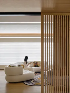 A modern minimalist living room with a white circular sofa, colorful pillows, and a wooden floor.