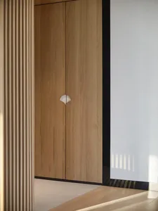 A modern minimalist wooden cabinet with a unique white circular handle.