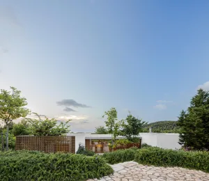 A modern residential architecture with white walls and greenery surrounding the building.