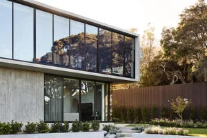 Modern residential home with large glass windows and concrete exterior.