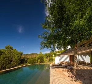 A modern residential exterior features wooden deck, glass walls, and stone accents.