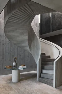 A modern interior design featuring a concrete staircase with a glass table in front.